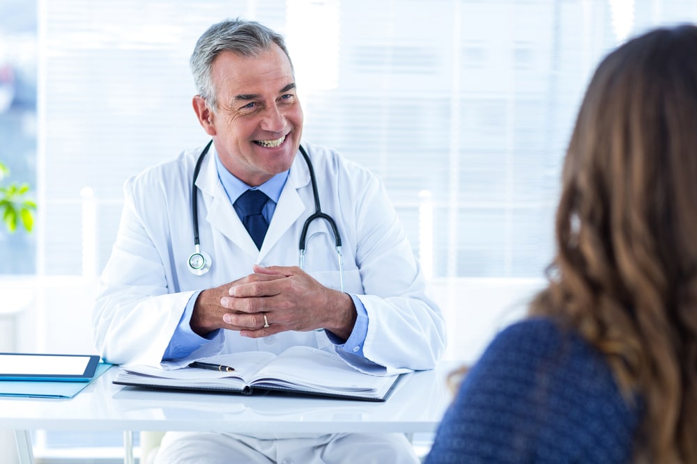 Smiling,Male,Doctor,Talking,To,Woman,White,Sitting,In,Clinic 1765843304 7d4c749d922d4995afb2f350b2670fcf 1